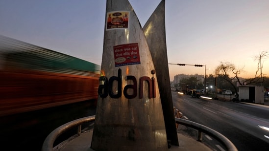 Traffic moves past the logo of the Adani Group installed at a roundabout on the ring road in Ahmedabad, India.(REUTERS)