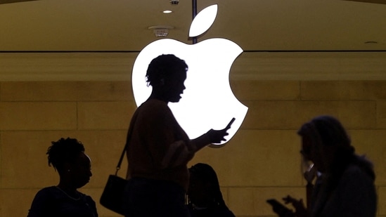 People walk past the Apple logo