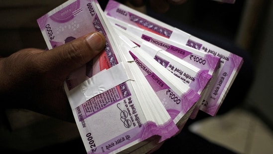 A cashier displays the new 2000 Indian rupee banknotes inside a bank.(REUTERS)