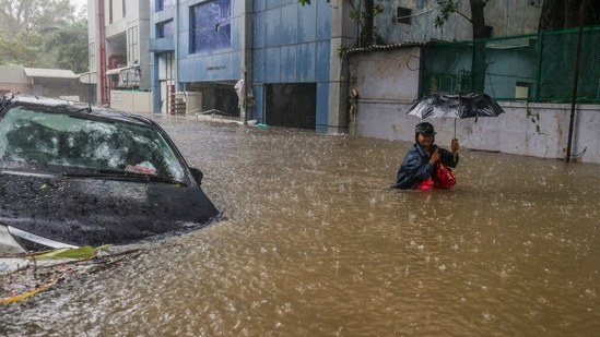 A man wades through a waterlogged road during heavy rain owing to Cyclone Michaung, in Chennai,(PTI)