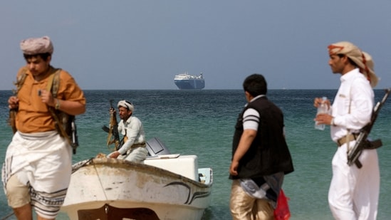 Armed men stand on the beach as the Galaxy Leader commercial ship, seized by Yemen's Houthis last month, is anchored off the coast of al-Salif in Yemen on December 5.(Reuters)