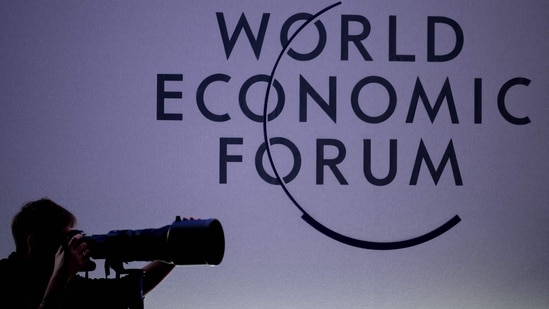 A press photographer works next to the logo of the World Economic Forum (WEF) at the opening of their annual meeting in Davos on January 15, 2024. (AFP)