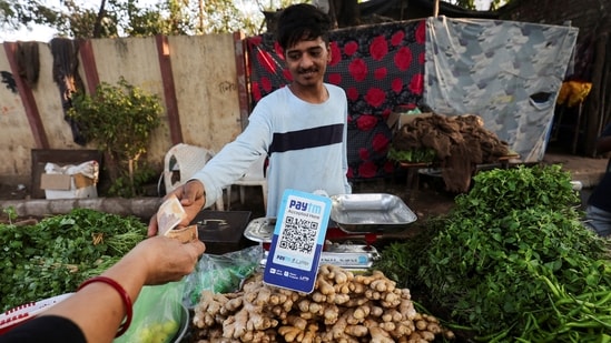 A customer pays cash to buy vegetables next to a QR code of Paytm, a digital payments firm, on display at a roadside market in Ahmedabad, India, February 5, 2024.REUTERS/Amit Dave(REUTERS)