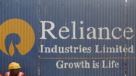 FILE PHOTO: Labourers rest in front of an advertisement of Reliance Industries Limited at a construction site in Mumbai.